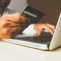 Persona realizando transacción por internet con tarjeta de crédito en su mano